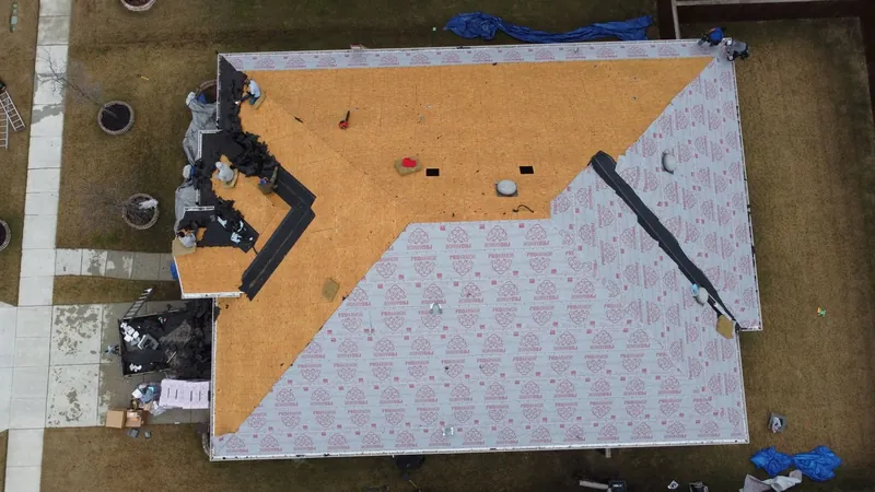 Drone view of a roof mid replacement, decking exposed and underlayment going down
