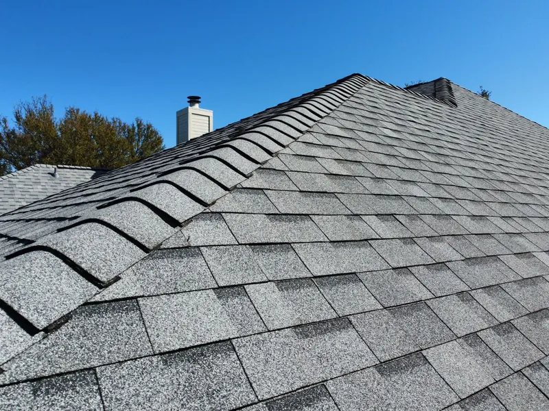 Close-up of new architectural shingles and ridge cap against a blue sky